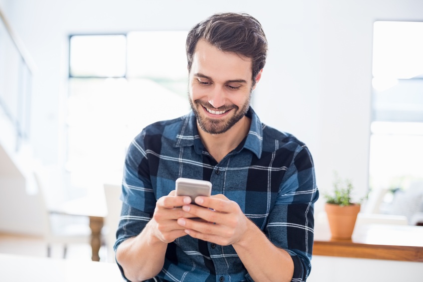 kobieta w jednej dłoni trzyma telefon komórkowy, a w drugiej kawę