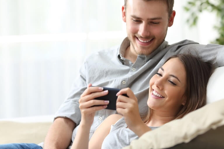 Couple smile and look at smartphone screen
